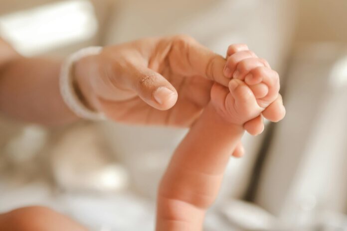 Dziecięca rączka zaciśnięta wokół palca dorosłej osoby